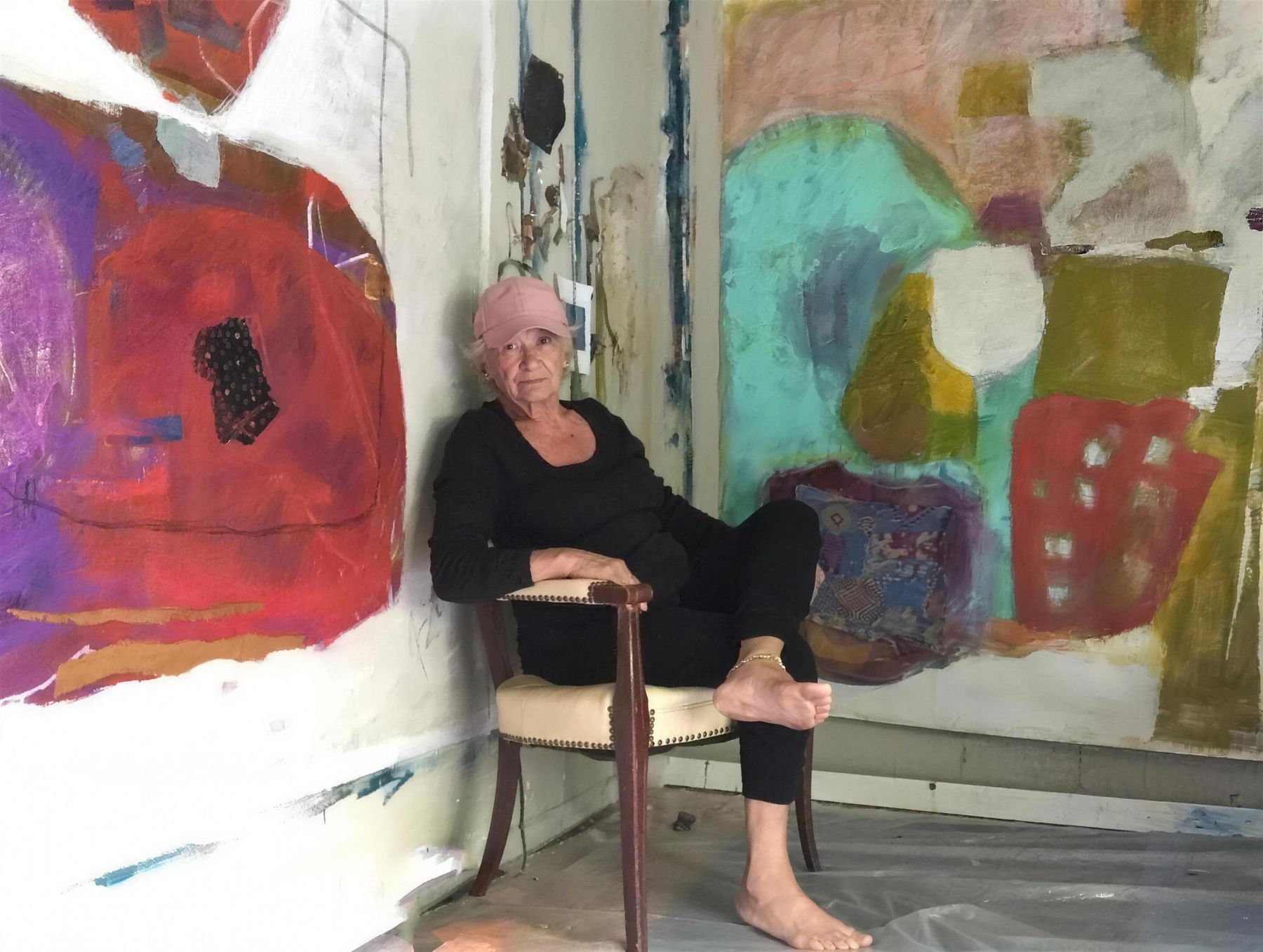 Yvonne Stevenson seated in her studio in front of two large canvases